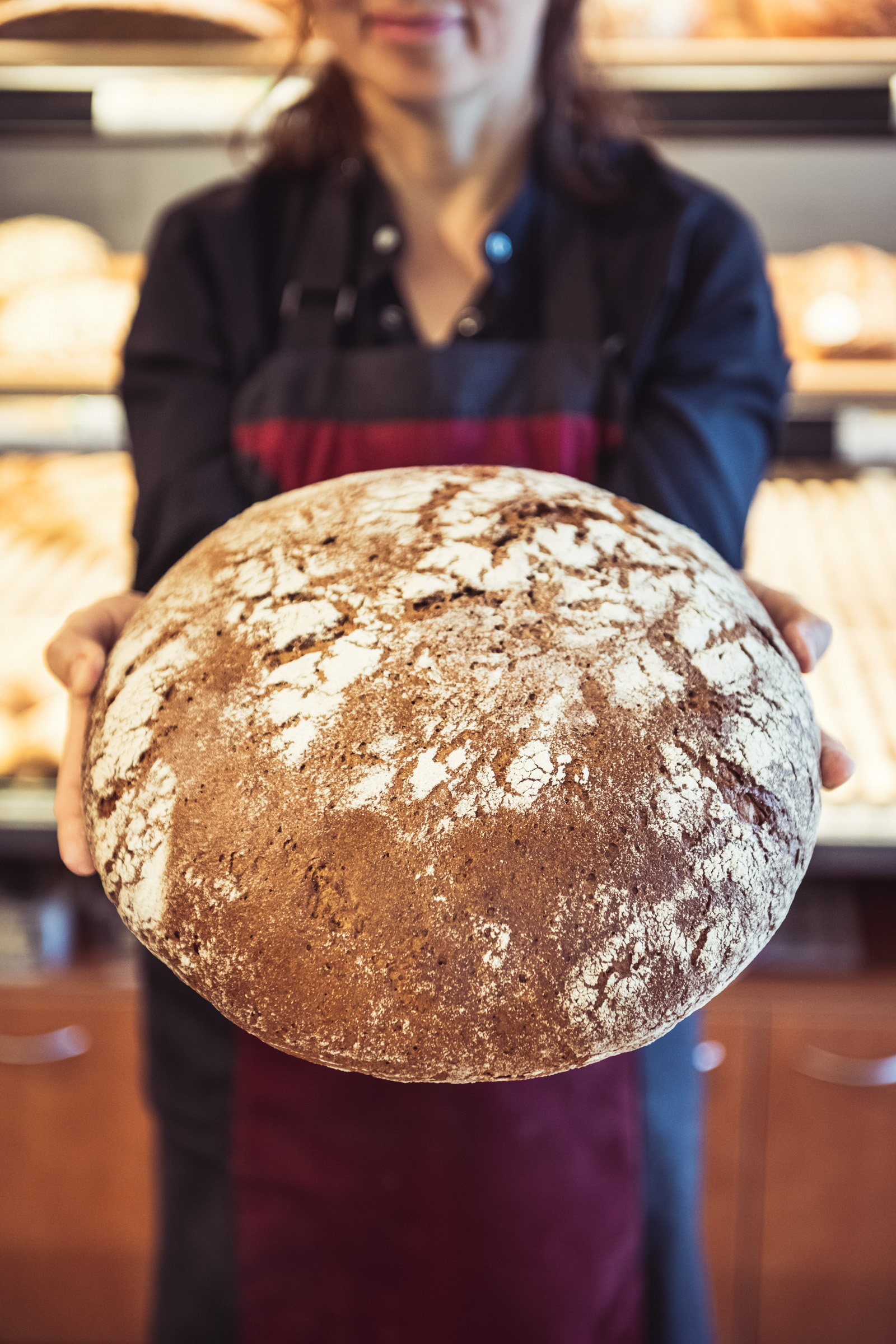 Frau in Bluse und Schürze mit Brot im Lebensmitteleinzelhandel